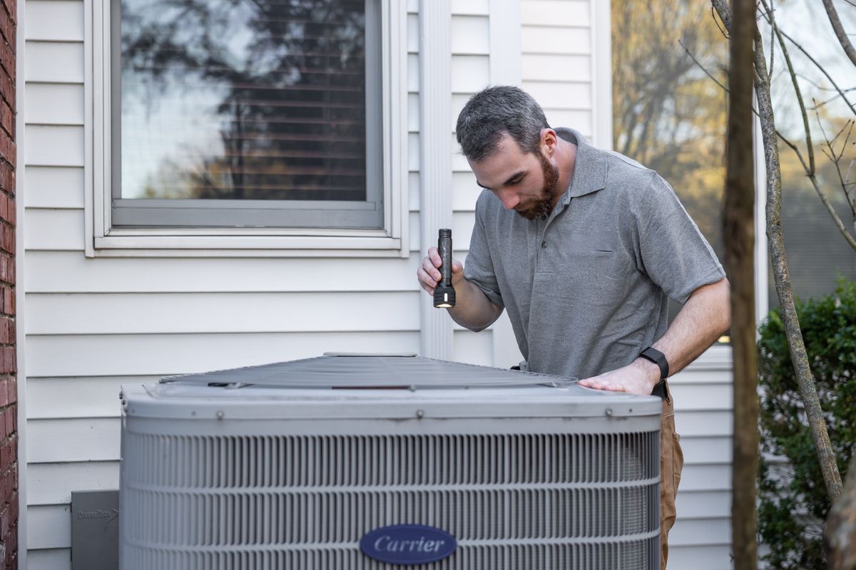 Technician inspecting an outdoor HVAC unit